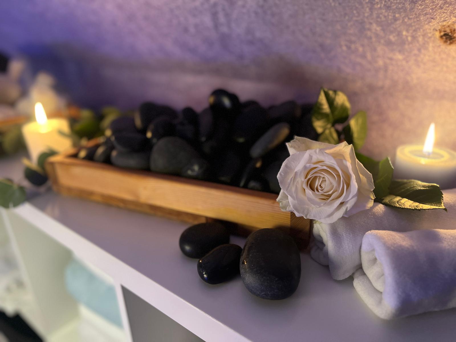 Hot-Stone-Steine mit Kerzen und weißer Rose